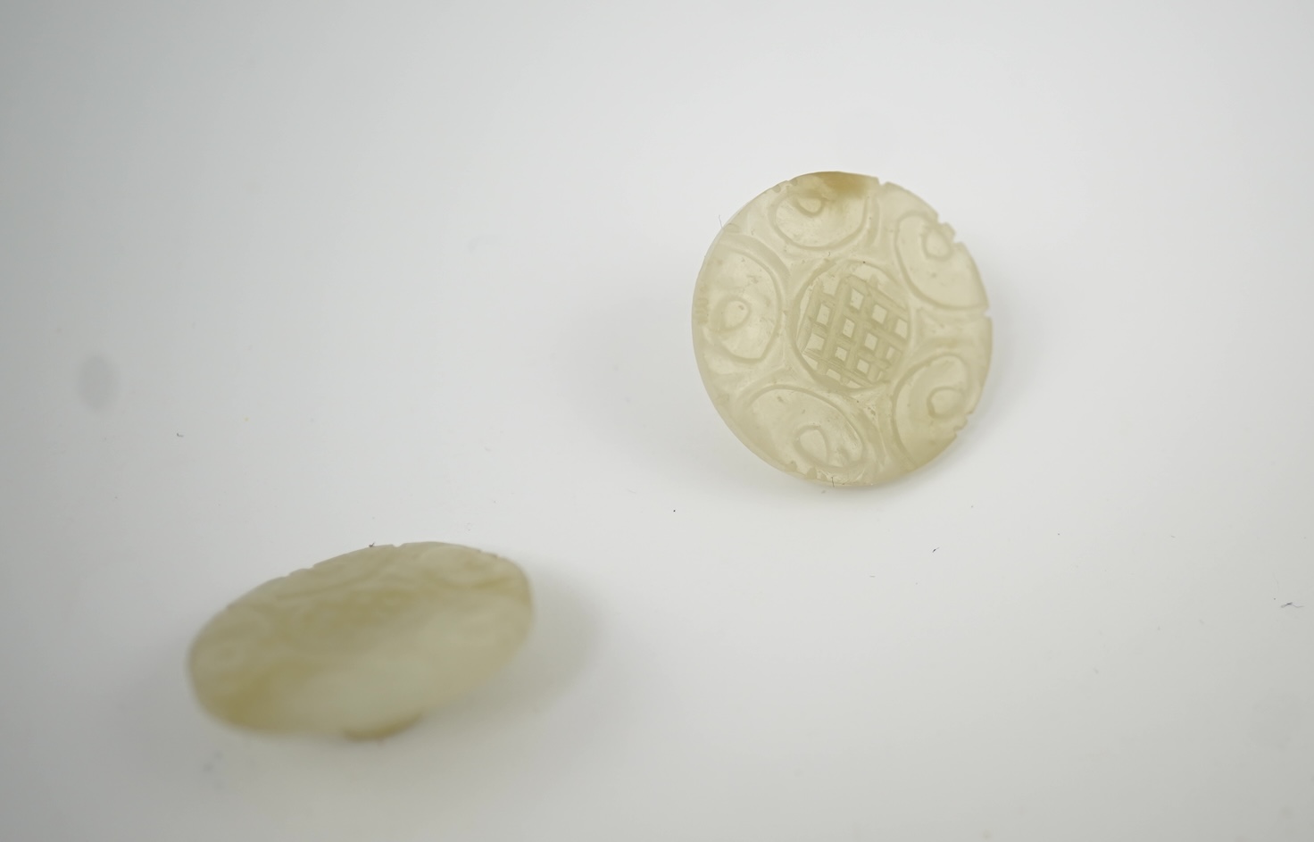 A set of five Chinese pale celadon jade robe buttons, 19th century